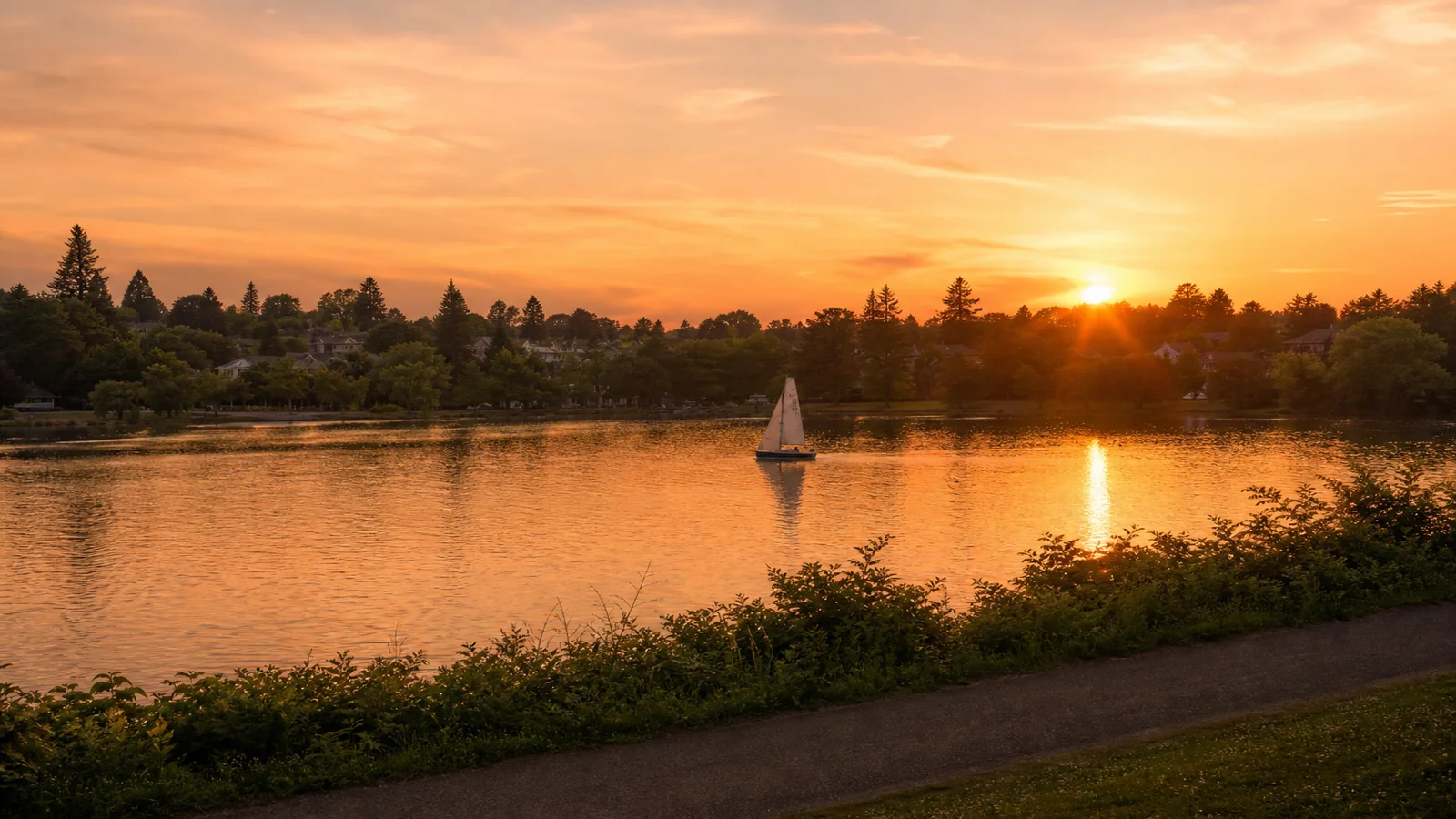 Sunset over Green Lake in Seattle with a small sailboat on calm water